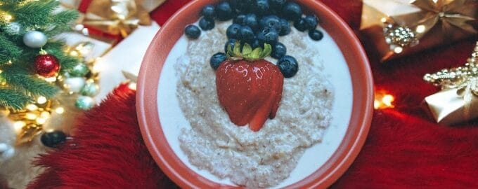 A festive breakfast bowl featuring oatmeal topped with a strawberry and blueberries.