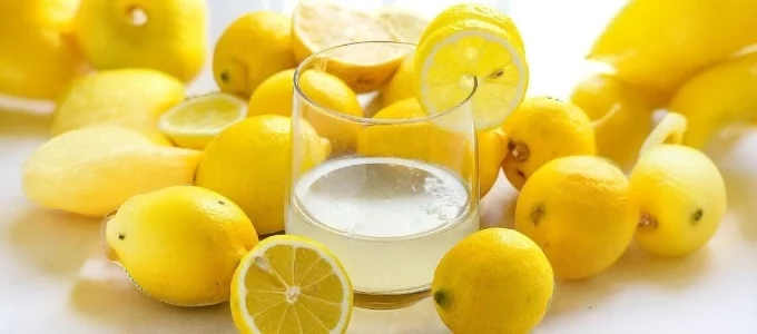 A glass of lemon juice surrounded by whole