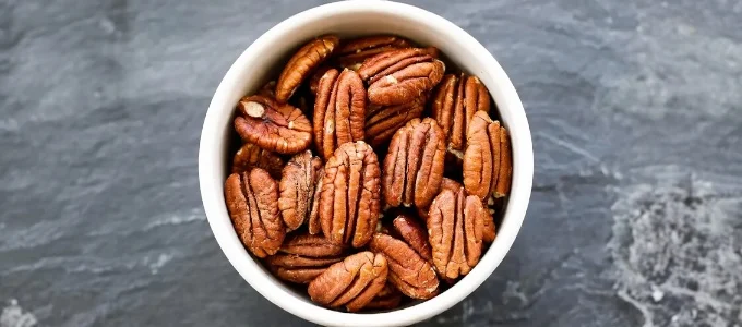 A bowl of unshelled pecans on a dark gray