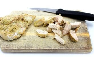 Cooked, seasoned chicken sits on a wooden cutting