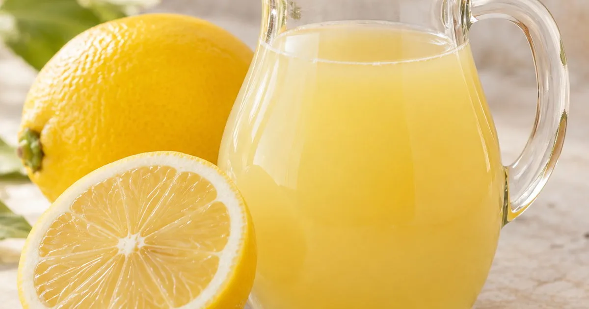 Fresh lemon juice in a glass pitcher with lemons