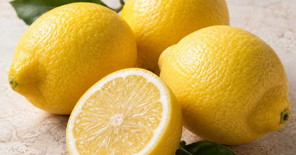 Fresh whole and halved lemons with green leaves