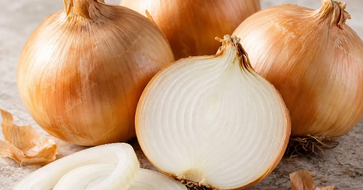 Fresh yellow onions with a halved onion and sliced onion rings